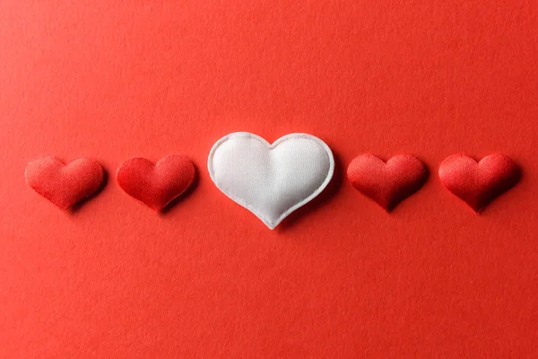 Red and white textile hearts on red paper — Stock Photo, Image