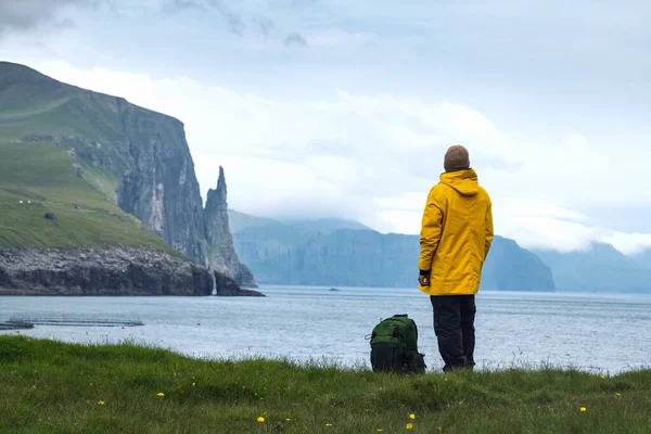 Turysta z plecakiem w żółtej kurtce patrzy na klify Witches Finger — Zdjęcie stockowe