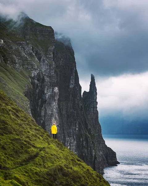 Turysta z plecakiem w żółtej kurtce patrzy na klify Witches Finger — Zdjęcie stockowe