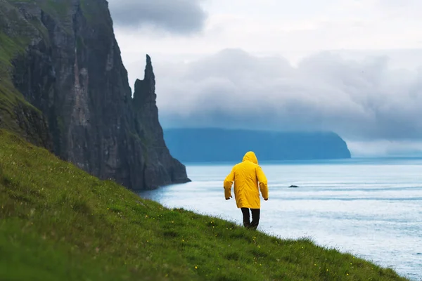 Tourist mit Rucksack in gelber Jacke blickt auf Hexenfingerklippen — Stockfoto