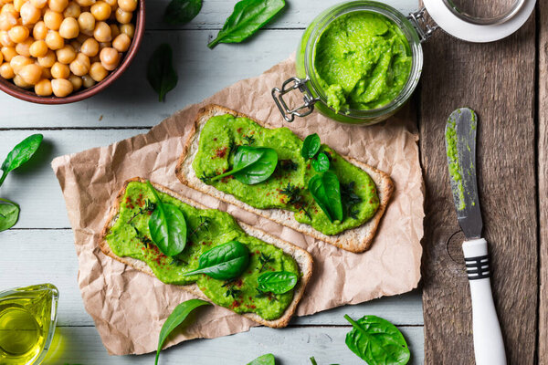 Two crackers with green spinach humus