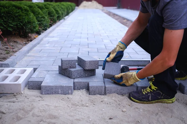 The master in yellow gloves lays paving stones — Stock Photo, Image