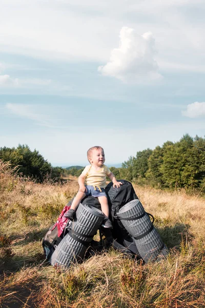 Small kid sitting on tourists backpacks — Stock Photo, Image