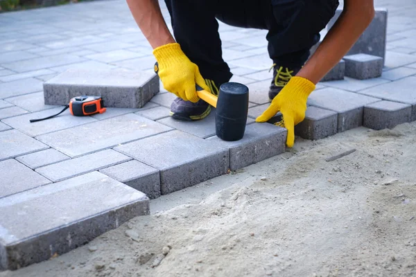 The master in yellow gloves lays paving stones — Stock Photo, Image