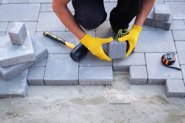 The master in yellow gloves lays paving stones — Stock Photo, Image