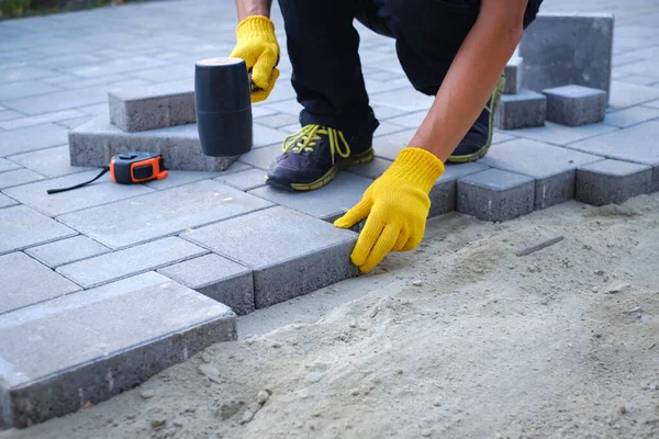 The master in yellow gloves lays paving stones — Stock Photo, Image