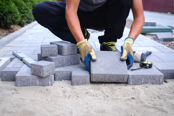 The master in yellow gloves lays paving stones — Stock Photo, Image