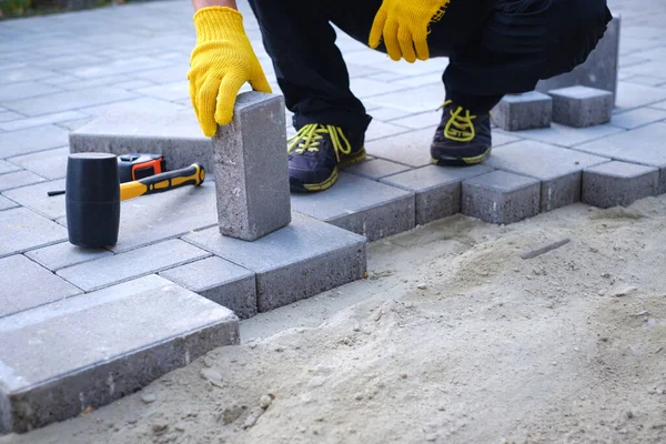 The master in yellow gloves lays paving stones — Stock Photo, Image