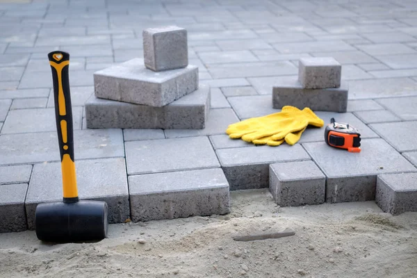 O mestre em luvas amarelas coloca pedras de pavimentação — Fotografia de Stock