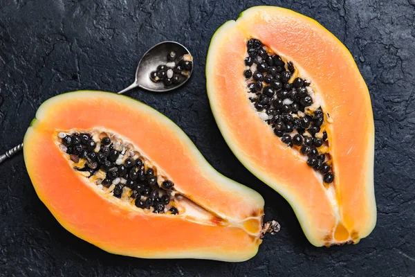 Geschnittene Papaya mit Silberlöffel auf schwarzem Betonhintergrund — Stockfoto