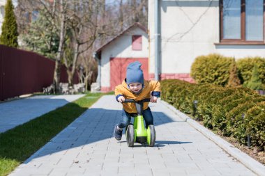 Bisikletli küçük çocuk evinin yakınındaki kaldırım yolunda