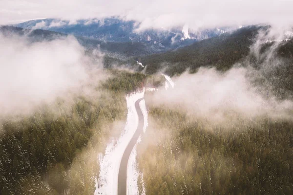 Vol au-dessus des montagnes d'hiver avec serpentine de route — Photo