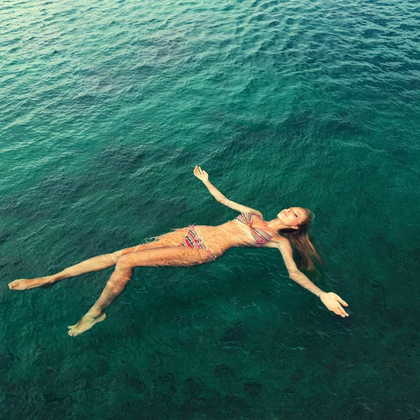 Женщина в бикини отдыхает, лежа на воде — стоковое фото