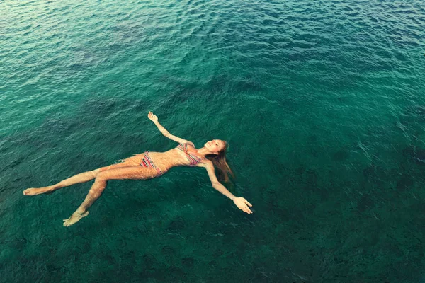 Woman in bikini relaxing lying on the water — Stock Photo, Image