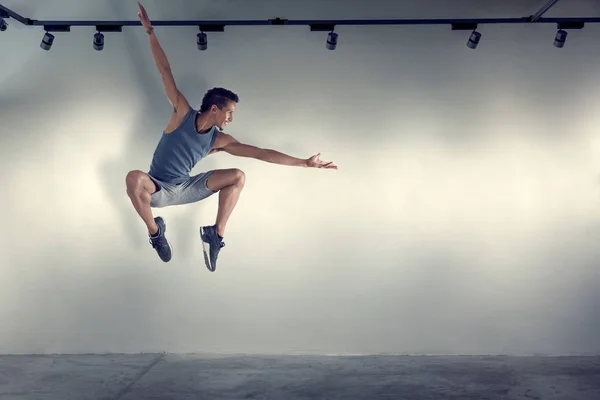 Joven saltando frente a la pared gris — Foto de Stock