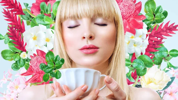 Femme avec tasse de boisson devant le fond des fleurs — Photo