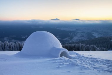 Büyük yuvarlak Igloo karla kaplı dağlar üzerinde duruyor.