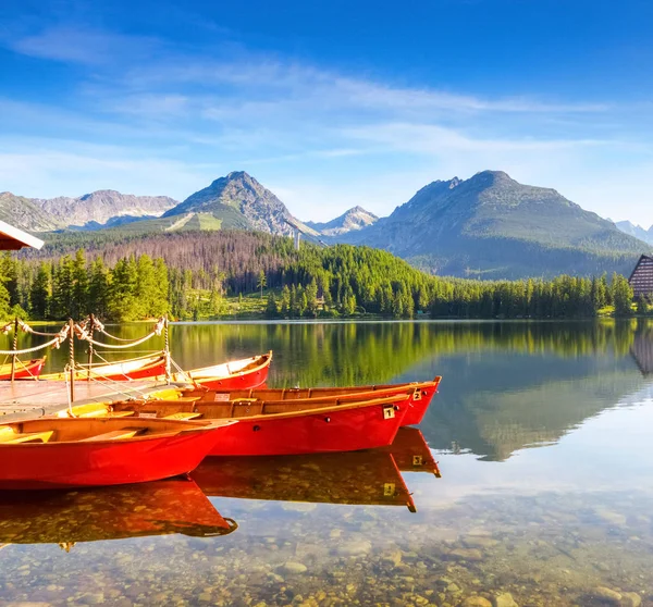 Dreamy red boats stand at the pier on a quiet lake. — Stock Photo, Image