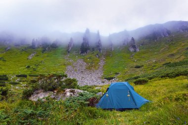 Yalnız turist çadır bir çayır üzerinde duruyor.