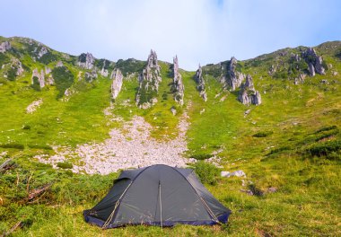 Yalnız turist çadır bir çayır üzerinde duruyor.