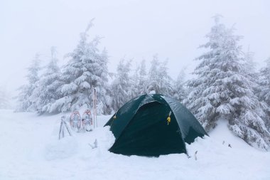 Kar ile kaplı çadırın yakınında yürüyüş sopa are.