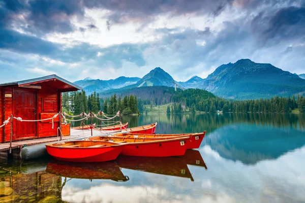 Boats stand near wooden bridge and a hut on a mountain lake. — Stock Photo, Image