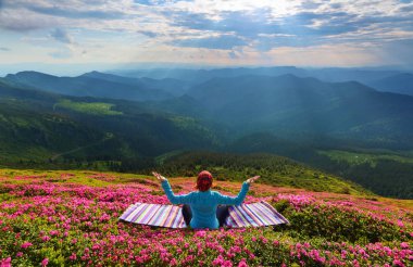 Pembe orman gülleri içinde'nın bahçesinde kız içinde lotus duruş çizgili halının üstünde oturuyor .