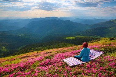 Pembe orman gülleri içinde'nın bahçesinde kız içinde lotus duruş çizgili halının üstünde oturuyor . 