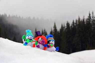 Komik, küçük, renkli şapka, eşarp ve eldiven, Puslu Ladin orman yüksek dağlarda çerçevede bir karda duran giymiş bir kroşe kanca snowmen ile üç örme.