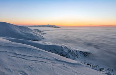 Fantastik gündoğumu, soğuk bir kış sabahı, kalın bir sis ve ufukta Chornohora dağ sırasını aydınlatır. Güzel manzara. Duvar kâğıdı karlı arka plan. Konum: Carpathian, Ukrayna, Avrupa