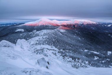 Soğuk kış gününde güzel bir manzara. Harika bir gün doğumu. Kar beyazı tepeleri olan yüksek bir dağ. Karlı arkaplan.