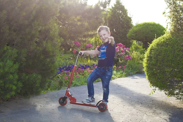 Jongen spelen op zijn scooter in het plaatselijke park. — Stockfoto