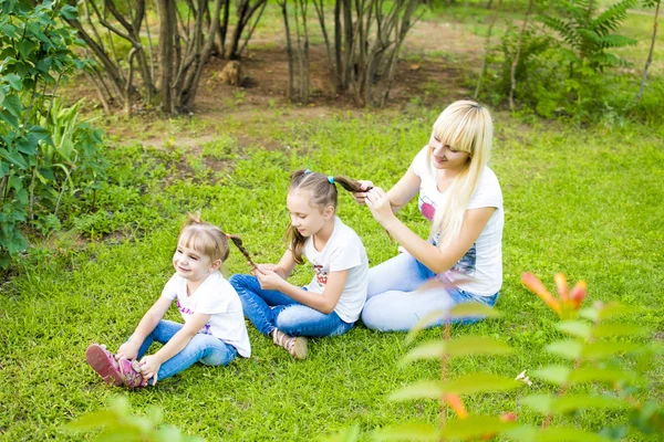 Jeune mère et deux filles jouant dans l'herbe Images De Stock Libres De Droits
