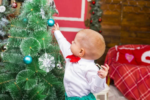 Mignon petit enfant décorant arbre de Noël avec des perles bleues Images De Stock Libres De Droits