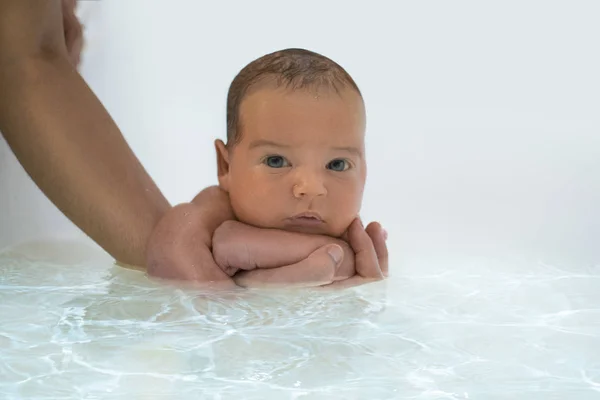 Новорожденный ребенок плавает с помощью рук родителей впервые. У ребенка желтуха новорожденного. Сосредоточься на головке ребенка — стоковое фото