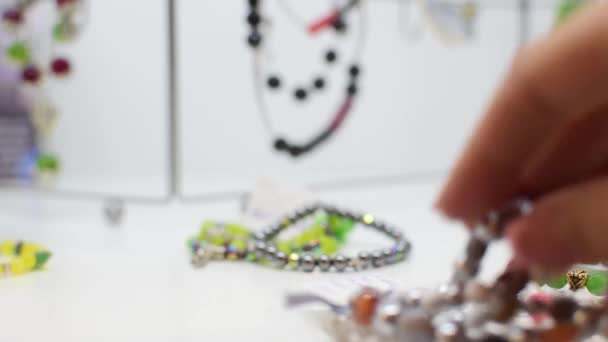 Šperky zelená černá bílá, náhrdelník a náramek closeup na bílé police nebo na bílém stole. — Stock video