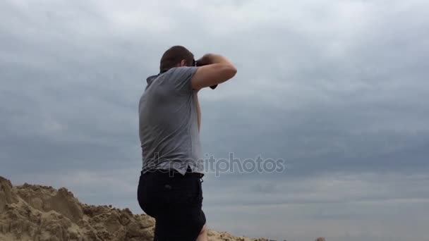 Fotógrafo em movimento. Jovem fotógrafo bonito mantém sua câmera enquanto atira . — Vídeo de Stock