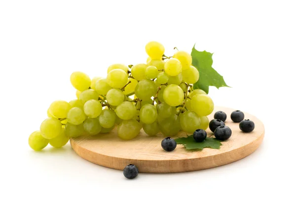 Ramo de uvas verdes y arándanos en un carnicero de madera . —  Fotos de Stock