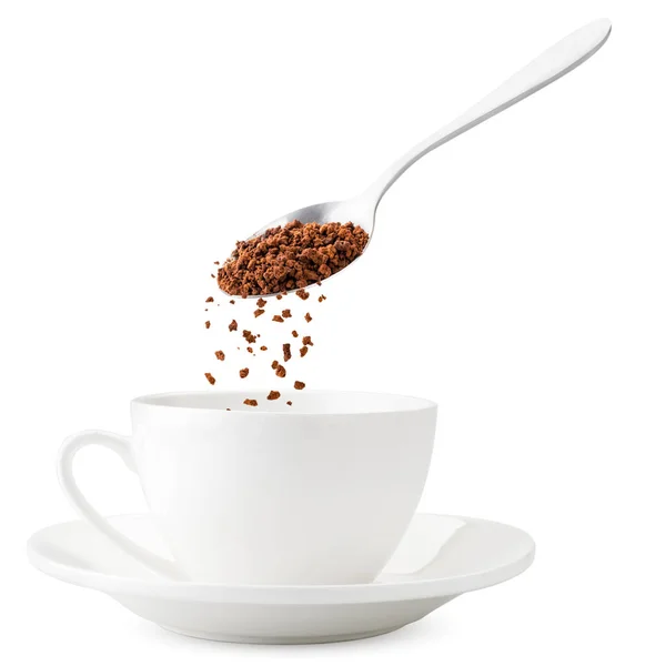 Instant-Kaffee ergießt sich aus einem Löffel in eine Tasse, in Großaufnahme schwebt er auf weißem Hintergrund. Zubereitung des Kaffees. isoliert — Stockfoto
