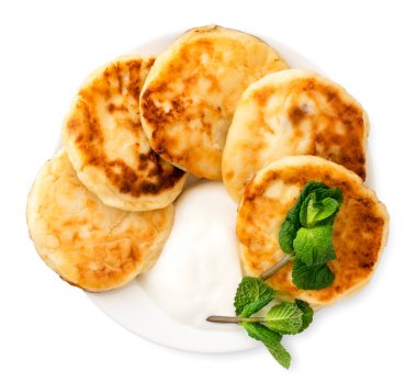 Cottage cheese pancakes with sour cream and mint. Top view isolated on white