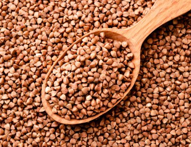 Buckwheat in a wooden spoon. Buckwheat background top view