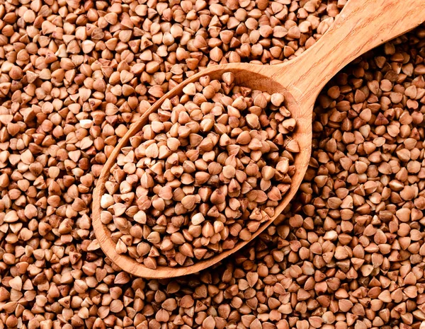 Buckwheat in a wooden spoon. Buckwheat background top view — Stock Photo, Image