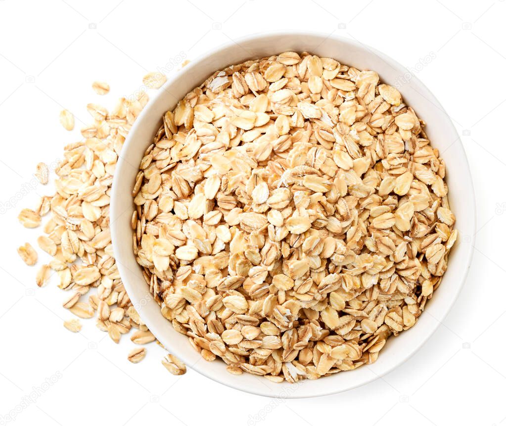 Oatmeal in a plate and scattered on a white background. The view from the top