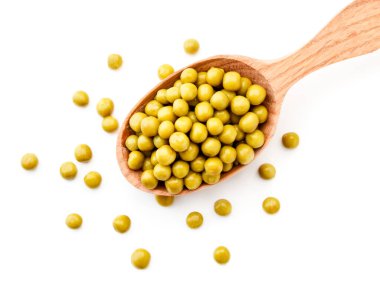 Ahşap bir kaşıkta konserve bezelye konservesi ve beyaz bir arka plana serpilmiş. Yukarıdan görünüşü