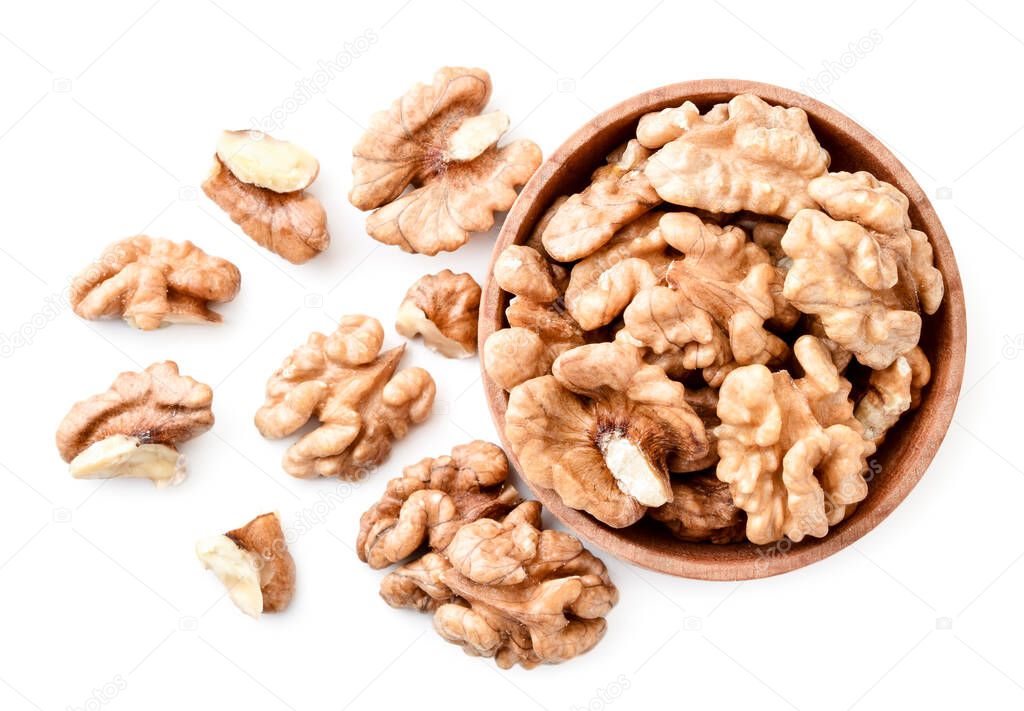 Walnut peeled in a wooden plate and scattered on a white background. The view from the top.