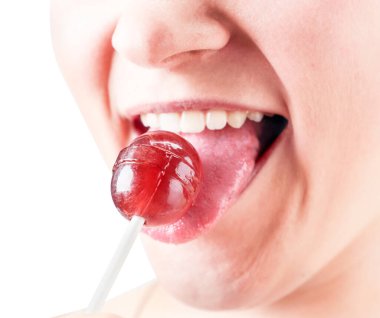 Kız beyaz arka planda lolipop yalıyor. İzole edilmiş