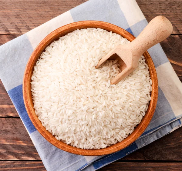 Rice in a wooden plate and spatula, background. The view from top — Stock Photo, Image