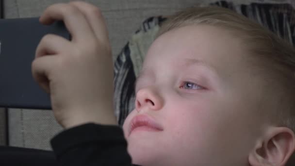 7 let dítěte/boy pomocí smartphone v noci v posteli — Stock video