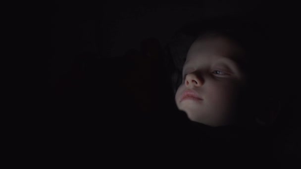 Enfant garçon de 7 ans utilisant un smartphone la nuit au lit 