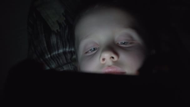 7 years old child boy using smartphone at night in bed — Stock Video